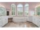Primary bathroom with a soaking tub beneath arched windows, double vanities, and marble floors at 4770 Powers Park Ne Ct, Marietta, GA 30067