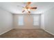 Neutral bedroom features a ceiling fan, carpeted floor, and two windows with light streaming in at 6509 Charter Way, Lithonia, GA 30058