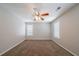 Neutral bedroom features a ceiling fan, carpeted floor, and two windows with light streaming in at 6509 Charter Way, Lithonia, GA 30058