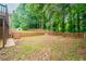 Spacious backyard featuring a wooden fence, retaining wall and mature trees, perfect for outdoor entertaining at 4495 Riders Ridge Trl, Snellville, GA 30039