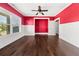 Open-concept living room with red accent wall, white wainscoting, and hardwood flooring at 90 Alcovy Reserve Way, Covington, GA 30014