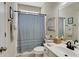 Neutral toned bathroom with a vanity, mirror, shower with blue striped curtain and artwork on the walls at 125 Rabbits Run, Fayetteville, GA 30215