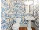 Charming powder room featuring blue and white patterned wallpaper, pedestal sink, and hardwood floors at 635 Wilson Nw Rd, Atlanta, GA 30318