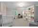 Bright bedroom featuring a white crib, a built-in bookcase and an adjacent desk with natural light at 1217 Club Walk Ne Dr, Brookhaven, GA 30319
