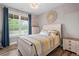 A cozy bedroom with wood floors, a decorative wall hanging, and a sunny window with blue curtains at 1423 Hillcrest Rd, Bowdon, GA 30108