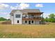 Back of a stunning two-story white farmhouse with a large covered deck and expansive yard at 1423 Hillcrest Rd, Bowdon, GA 30108