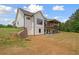 The back of an elegant two-story white farmhouse with a covered deck overlooking a lush lawn at 1423 Hillcrest Rd, Bowdon, GA 30108