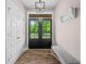 Bright foyer with a glass panel front door, coat closet, bench, wood floors, and stylish light fixture at 1423 Hillcrest Rd, Bowdon, GA 30108