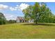 Beautiful home featuring vertical siding, a welcoming front porch, dark window frames, and a large tree at 1423 Hillcrest Rd, Bowdon, GA 30108