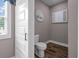 A cozy powder room with wood-look flooring, gray walls, decorative prints, and a white toilet at 1423 Hillcrest Rd, Bowdon, GA 30108
