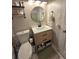 Updated bathroom featuring a wooden vanity, modern fixtures, and a stylish round mirror at 5108 Hackett Ne St, Covington, GA 30014