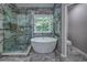 Bright main bathroom features soaking tub, marble floors and walls, and glass shower at 1325 Starboard Way, Cumming, GA 30041