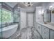 Bright main bathroom offers a soaking tub, large windows, and marble floors and walls at 1325 Starboard Way, Cumming, GA 30041
