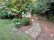 Charming backyard with stone pathway leading to a shed surrounded by mature trees and greenery at 2610 Stokesley Way, Snellville, GA 30078