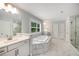 Spacious bathroom with soaking tub, glass shower, and white marble tile at 771 Phil Haven Ln, Kennesaw, GA 30152