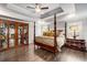 Well-lit bedroom with a four-poster bed, wooden floors, and decorative storage at 771 Phil Haven Ln, Kennesaw, GA 30152
