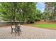 Paver patio with outdoor seating surrounded by mature trees and lawn, offering privacy and space for outdoor enjoyment at 6695 Buckingham Cir, Cumming, GA 30040