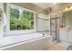 Bright primary bathroom with a soaking tub and glass shower at 6695 Buckingham Cir, Cumming, GA 30040