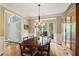 Sunlit dining room boasts an arched entry, wood floors, and stylish chandelier at 6695 Buckingham Cir, Cumming, GA 30040