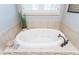 Luxurious soaking tub with tile surround, decorative accents, and jacuzzi jets at 9967 Devonshire St, Douglasville, GA 30135