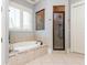 Elegant bathroom with a soaking tub, walk-in shower, and a window with plantation shutters at 9967 Devonshire St, Douglasville, GA 30135