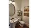 Stylish powder room featuring a pedestal sink, round mirror, and decorative artwork at 1105 River Laurel Dr, Suwanee, GA 30024