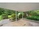 Covered back patio with concrete flooring, framed with a brick border, and surrounded by lush greenery at 180 Butterfield Ln, Fayetteville, GA 30214
