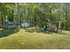 Large, grassy backyard featuring mature trees, playground equipment, and storage shed, perfect for Gathering enjoyment at 1007 Wayne Dr, Snellville, GA 30078