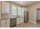 This well-lit kitchen includes white cabinets, stainless steel appliances, granite countertops, and a stainless steel refrigerator at 1967 West John Calvin Ave, Atlanta, GA 30337