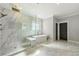 Modern bathroom with glass shower, soaking tub, and white marble tiled walls at 704 Rock Springs Rd, Lawrenceville, GA 30043