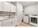 Well-lit laundry room with white cabinets, tile floor, and modern washer and dryer at 704 Rock Springs Rd, Lawrenceville, GA 30043