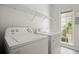 Functional laundry room with modern washer and dryer, shelving, and a window for natural light offering convenience at 1050 Shady Valley Pl, Atlanta, GA 30324