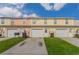 Townhouse featuring individual garages and driveways, complemented by green lawns under a bright sky at 4544 Parkview Sq, Atlanta, GA 30349
