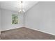 A gray bedroom with brown carpet, a window with natural light, and a decorative light fixture hanging from the ceiling at 6541 Lazy Creek Ct, Lithonia, GA 30058