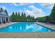 Large community pool with clear blue water surrounded by lush greenery and a privacy fence at 2428 Black Forest Dr, Conyers, GA 30012