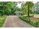 Side view of home featuring a long driveway leading to an attached garage with beautiful trees and greenery surrounding the property at 299 Fieldview Dr, Auburn, GA 30011