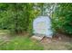 Outdoor white storage shed with double doors in a lush, green backyard setting, providing extra storage space at 299 Fieldview Dr, Auburn, GA 30011