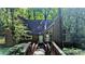 Charming home exterior with a wooden bridge leading to the front door, surrounded by lush greenery and mature trees at 3246 Able Ct, Marietta, GA 30062