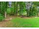 Beautiful, landscaped backyard features a lush lawn, mature trees and stone retaining walls at 150 Wilbanks St, Buford, GA 30518