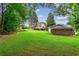 Expansive backyard featuring lush green lawn, mature trees, and a charming home with a deck at 150 Wilbanks St, Buford, GA 30518