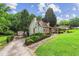Exterior view showcasing the home's unique design, a long driveway, and well-maintained landscaping at 150 Wilbanks St, Buford, GA 30518