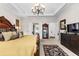 Well-lit bedroom with decorative chandelier, neutral walls, carpet, and dark wood furnishings at 248 Montrose Dr, Mcdonough, GA 30253