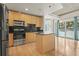 Modern kitchen with stainless steel appliances, wood cabinets, and an island, with a large window and balcony access at 250 Pharr Ne Rd # 208, Atlanta, GA 30305