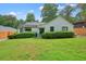 Quaint home with white painted brick, green lawn, mature trees and trimmed hedge in the front yard at 3734 Powers Ferry Nw Rd, Atlanta, GA 30342