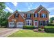 Brick two-story home features a lush green lawn, attached garage, and beautiful landscaping at 1124 Monarda Nw Way, Acworth, GA 30102