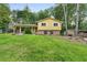 Charming two-story yellow home with brick foundation and lush front yard with mature trees at 2358 Dabney Ter, East Point, GA 30344