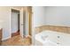 Bathroom featuring a soaking tub with tile surround and a view to the entryway at 4400 Old Allgood Cir, Stone Mountain, GA 30083