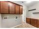 Functional laundry room featuring tile flooring, wooden cabinets, and utility connections for washer and dryer at 1045 Fords Crossing Nw Dr, Acworth, GA 30101