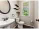 Charming powder room features pedestal sink, wood shelves and dark floors, and a window with natural light at 1045 Fords Crossing Nw Dr, Acworth, GA 30101