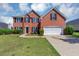 Charming two-story red brick home features a manicured lawn and a two-car garage at 1685 Great Oaks Dr, Lawrenceville, GA 30045